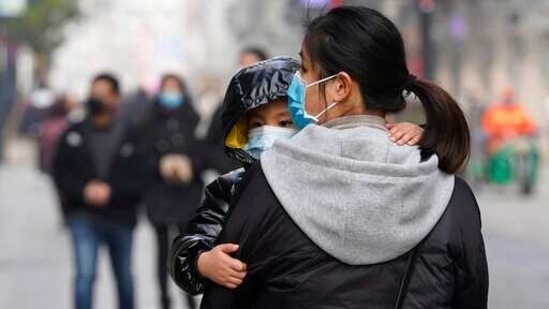 A child wearing a mask holds on to a woman as they walk through a popular shopping street in Wuhan in central China's Hubei province. The central Chinese city of Wuhan, where the coronavirus was first detected, has largely returned to normal. (AP) A child wearing a mask holds on to a woman as they walk through a popular shopping street in Wuhan in central China's Hubei province. The central Chinese city of Wuhan, where the coronavirus was first detected, has largely returned to normal. (AP)