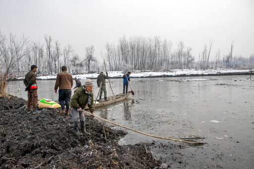 Ghulam Mohiuddin Dar, foreground, breaks ice with other wildlife officials in the frozen surface of a wetland. (AP) Ghulam Mohiuddin Dar, foreground, breaks ice with other wildlife officials in the frozen surface of a wetland. (AP)