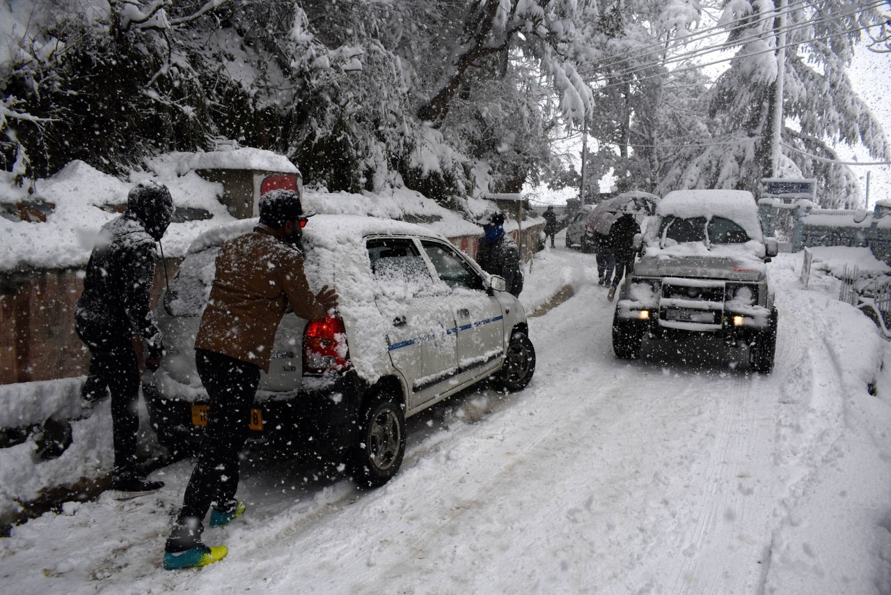 People pushing a car stuck on the snow-covered Sanjauli-IGMC Road in Shimla on Thursday. (Deepak Sansta /HT) People pushing a car stuck on the snow-covered Sanjauli-IGMC Road in Shimla on Thursday. (Deepak Sansta /HT)