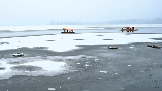 Men row their boat near a frozen portion of Dal Lake in Srinagar, Jammu and Kashmir on February 3. Flight operations at the Srinagar airport were affected on February 3 as most parts of the valley received snowfall. As many as 14 flights were cancelled due to poor visibility, ANI reported.(Tauseef Mustafa / AFP )
