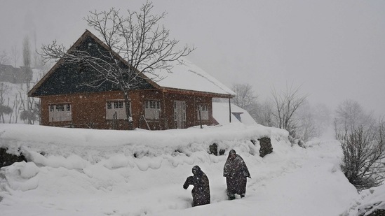 Commuters wade through a snow-covered road amid fresh snowfall at Ahlan village in South Kashmir on February 4. The air traffic to and fro Kashmir was restored on February 4 afternoon after the flight operations were affected due to accumulation of snow on the runway and poor visibility as most parts of the valley received overnight snowfall, PTI reported.(ANI)