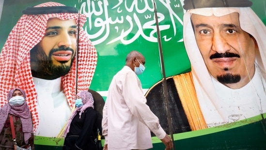 People wear face masks to protect against the spread of the coronavirus in front of a banner showing Saudi King Salman, right, and his Crown Prince Mohammed bin Salman, outside a mall in Jiddah, Saudi Arabia.(AP) People wear face masks to protect against the spread of the coronavirus in front of a banner showing Saudi King Salman, right, and his Crown Prince Mohammed bin Salman, outside a mall in Jiddah, Saudi Arabia.(AP)
