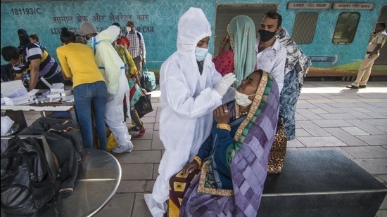 A healthcare worker screens travellers for Covid-19 infection at Dadar station in Mumbai. (HT FILE)
