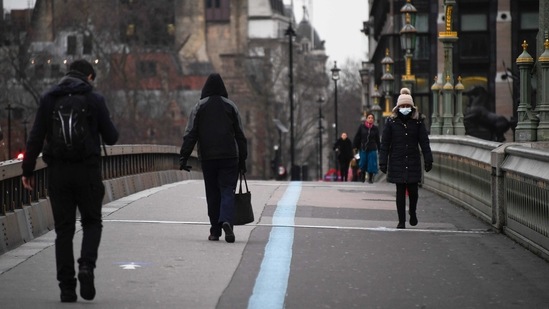 People wear protective face masks as they walk on Westminster Bridge in London. (AP)