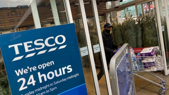 FILE PHOTO: A shopper wearing a protective face-mask passes christmas trees for sale and a sign indicating 24 hour opening times at a Tesco supermarket amid the spread of the coronavirus disease (COVID-19), London, Britain, December 6, 2020. REUTERS/Toby Melville/File Photo(REUTERS)