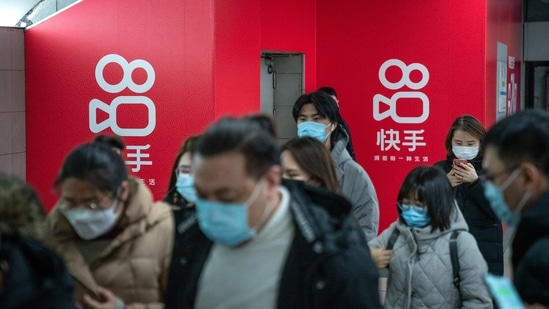 Passengers wearing protective masks walks past Kuaishou Technology advertisements at a subway station in Beijing, China.(Bloomberg)
