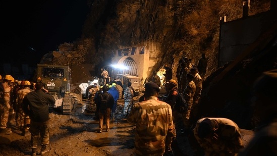 Indian army and rescue teams stand outside the entrance of a tunnel blocked with mud and debris during rescue operations in Tapovan of Chamoli district.