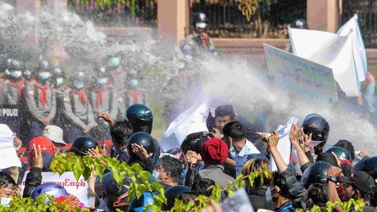 Myanmar police (in background) fire water cannon at protesters as they continue to demonstrate against the February 1 military coup in the capital Naypyidaw. (AP) Myanmar police (in background) fire water cannon at protesters as they continue to demonstrate against the February 1 military coup in the capital Naypyidaw. (AP)