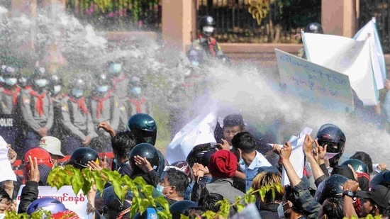 Myanmar police (in background) fire water cannon at protesters as they continue to demonstrate against the February 1 military coup in the capital Naypyidaw. (AP) Myanmar police (in background) fire water cannon at protesters as they continue to demonstrate against the February 1 military coup in the capital Naypyidaw. (AP)