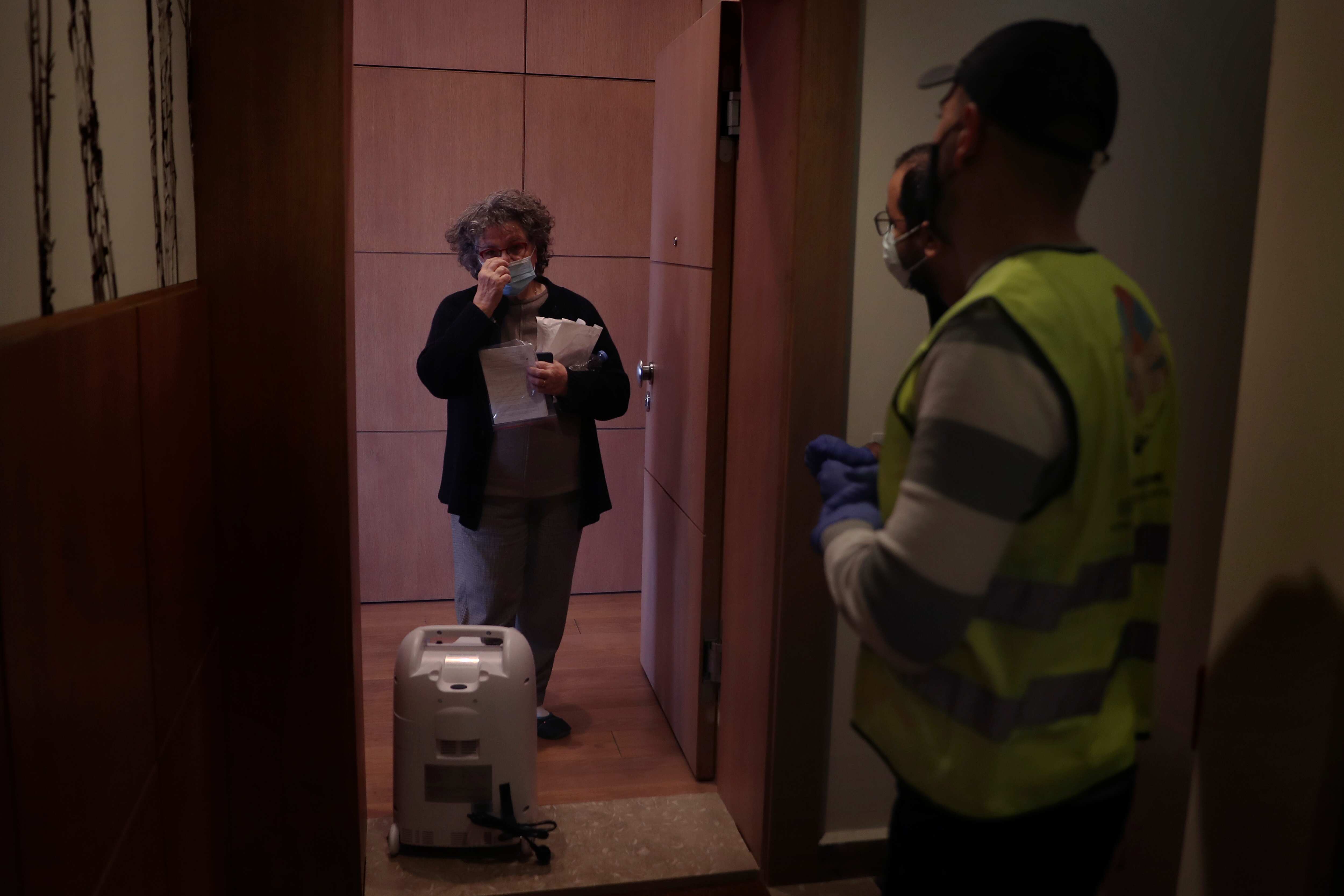 Members of Lebanese NGO Baytna Baytak Firas Minnawi, center, and Mario Suleiman, right, deliver an oxygen machine to COVID-19 patient in front of home so as to avoid infecting the staff in Beit Shebab, a mountain village 15 mile (24 km) north of Beirut, Lebanon,. The group of Lebanese activists are matching empty apartments and hotel rooms with nurses and doctors who are serving countless hours in the country's hospitals overwhelmed with COVID patients and who need a place to rest without endangering their families or elderly parents. (AP) Members of Lebanese NGO Baytna Baytak Firas Minnawi, center, and Mario Suleiman, right, deliver an oxygen machine to COVID-19 patient in front of home so as to avoid infecting the staff in Beit Shebab, a mountain village 15 mile (24 km) north of Beirut, Lebanon,. The group of Lebanese activists are matching empty apartments and hotel rooms with nurses and doctors who are serving countless hours in the country's hospitals overwhelmed with COVID patients and who need a place to rest without endangering their families or elderly parents. (AP)