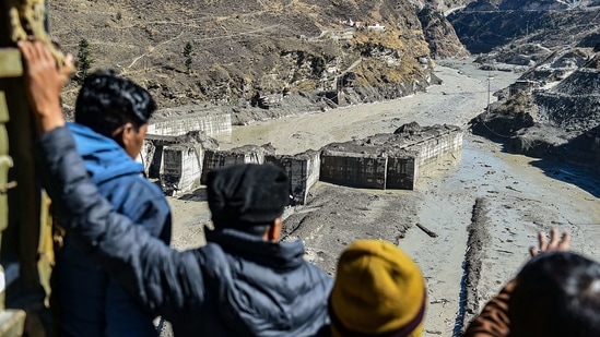 People look at the damaged Tapovan hydel project, a day after a glacier broke off in Joshimath causing massive flood in Dhauli Ganga River on February 8. As many as 32 bodies have been recovered so far from different areas hit by the glacier burst in Chamoli district.(Arun Sharma / PTI)