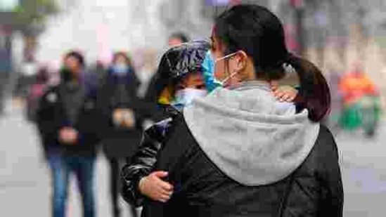 A child wearing a mask holds on to a woman as they walk through a popular shopping street in Wuhan in central China's Hubei province. (AP) A child wearing a mask holds on to a woman as they walk through a popular shopping street in Wuhan in central China's Hubei province. (AP)