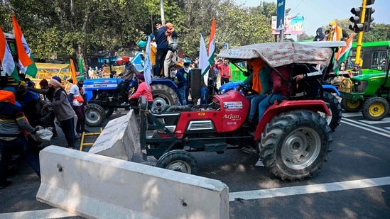 Farmers on tractors remove concrete barricades installed to prevent them from entering the city during the tractor rally in New Delhi on January 26. (Sajjad Hussain / AFP) Farmers on tractors remove concrete barricades installed to prevent them from entering the city during the tractor rally in New Delhi on January 26. (Sajjad Hussain / AFP)