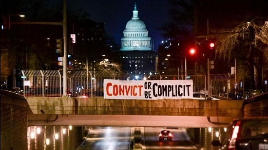 A banner reading "Convict or be complicit" is placed over a bridge with the US Capitol in the backdrop on the first day of the Senate impeachment trial against former president Donald Trump in Washington, DC on February 9, 2021. (REUTERS) A banner reading "Convict or be complicit" is placed over a bridge with the US Capitol in the backdrop on the first day of the Senate impeachment trial against former president Donald Trump in Washington, DC on February 9, 2021. (REUTERS)