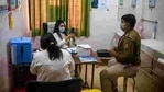A healthcare worker takes a photograph of a police officer with his vaccination card after administering Covid-19 vaccine.(AP) A healthcare worker takes a photograph of a police officer with his vaccination card after administering Covid-19 vaccine.(AP)