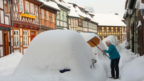 A resident clears the sidewalk in front of her front door of snow in Wernigerode, Germany, on February 9.(AP)