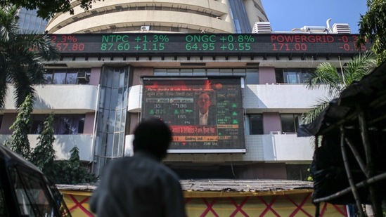 A person looks up at a screen and an electronic ticker board outside the Bombay Stock Exchange (BSE) building in Mumbai.(Bloomberg File Photo )