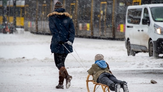 A woman pulls a child on a sledge at Berlin's Alexanderplatz square on February 9, 2021, when temperatures in the German capital remained at around minus ten. Many of the city's canals had frozen over earlier this week, prompting Berlin police to warn residents against stepping out on to the thin ice.(Astrid Vellguth / AFP)