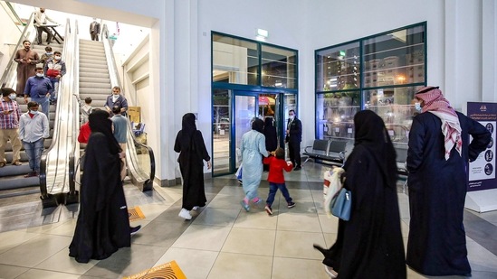 People exit a shopping mall as it closes early according to government-imposed Covid-19 coronavirus pandemic restrictions in Kuwait City.(AP)