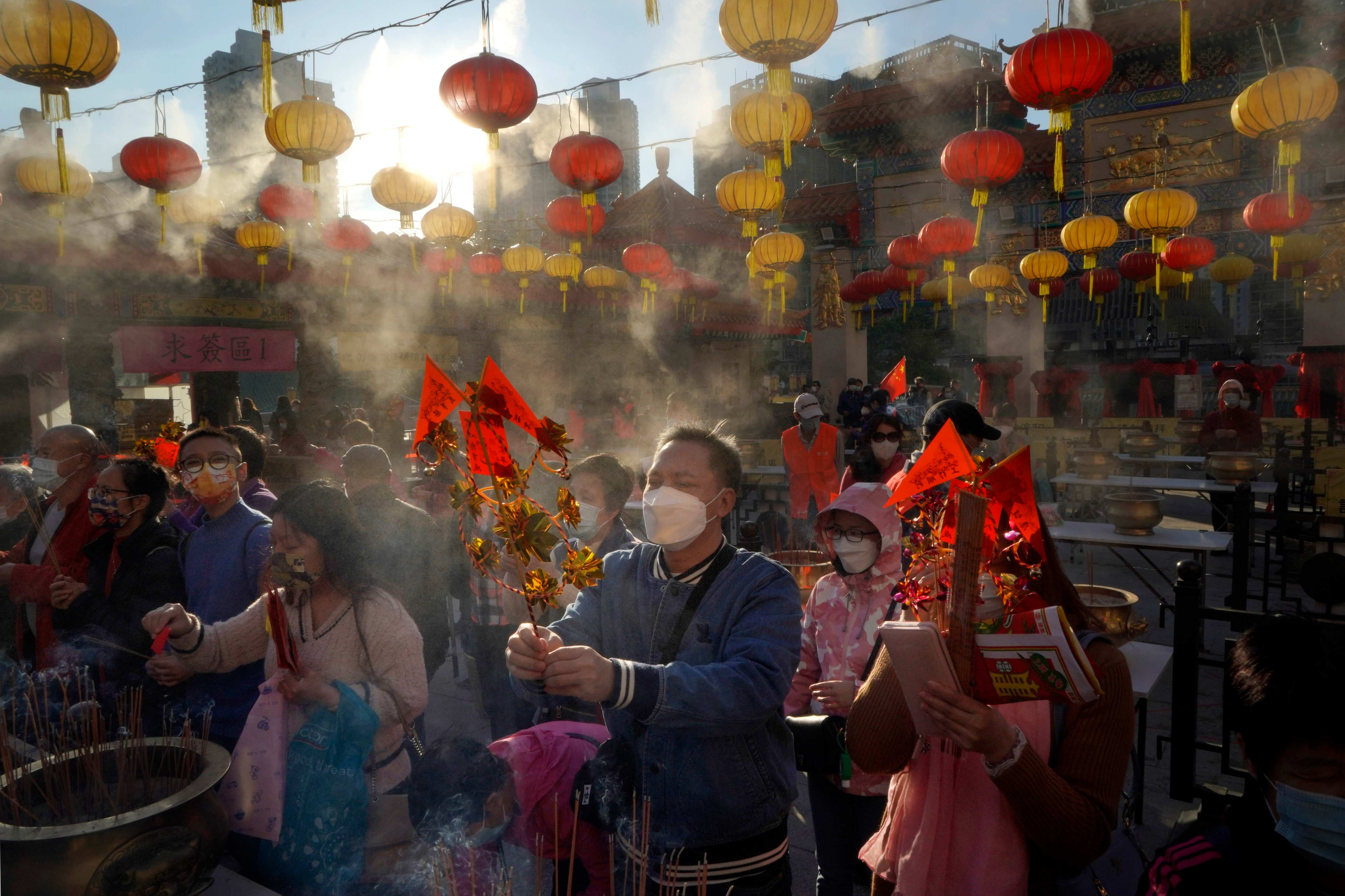 Worshippers wearing face masks to protect against the spread of the coronavirus burn joss sticks as they pray at the Wong Tai Sin Temple. (AP)