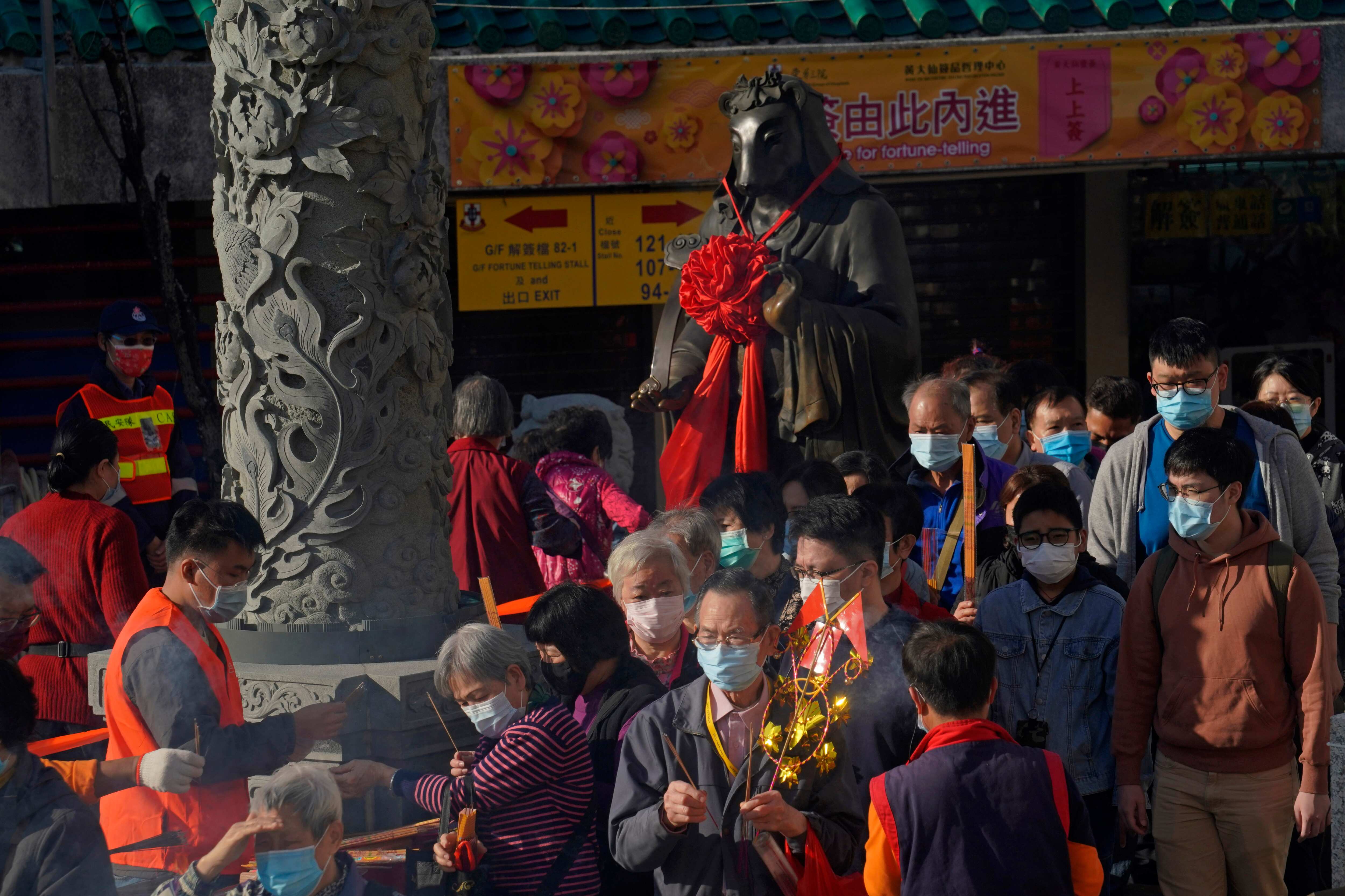 Worshippers wearing face masks to protect against the spread of the coronavirus, queue beside the statue of ox as they pray at the Wong Tai Sin Temple. (AP)