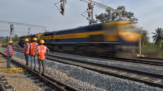 In this representative image, workers on contract for Indian Railways erect infrastructure for drawing electric cable lines over railway tracks for use by locomotives. (AFP) In this representative image, workers on contract for Indian Railways erect infrastructure for drawing electric cable lines over railway tracks for use by locomotives. (AFP)