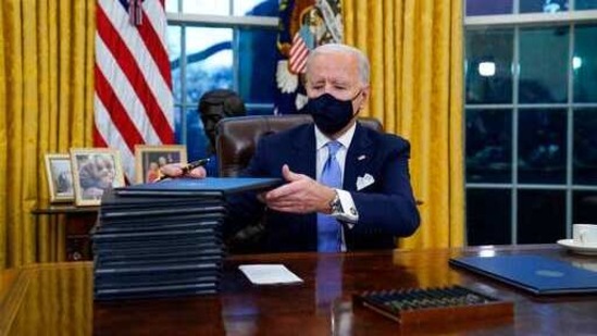 President Joe Biden signs his first executive orders in the Oval Office of the White House in Washington. (AP) President Joe Biden signs his first executive orders in the Oval Office of the White House in Washington. (AP)