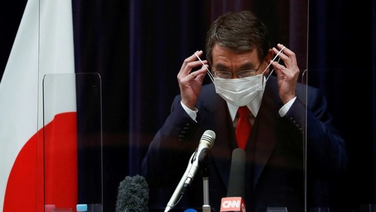 Japan's vaccination programme chief Taro Kono adjusts his protective face mask during a news conference. (Reuters)