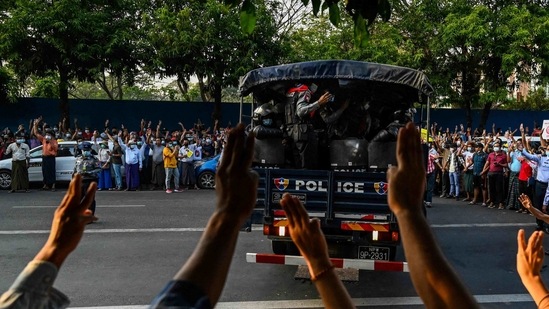 Protesters demonstrating against the military coup give the three-finger salute as police exit the National League for Democracy (NLD) headquarters in Yangon on February 15. Protesters opposed to the military coup blocked train services between Yangon and Mawlamyine on February 16, hours after a UN envoy warned the army of "severe consequences" for any harsh response to the pro-democracy demonstrations, Reuters reported.(Ye Aung Thu / AFP)