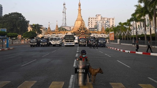 Lone police personnel seen next to a dog outside the Yangon City Hall (R) and Sule Pagoda (C) in Yangon on February 16. Security presence was low-key around the protest, with most police guarding key buildings in the city, AP reported(Sai Aung Main / AFP)