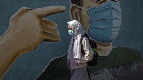 A Palestinian girl walks past a coronavirus-themed mural in Rafah in the southern Gaza Strip on February 16, 2021. - The Palestinian Authority accused Israel of refusing to allow some 2,000 coronavirus vaccine doses destined for Gaza health workers into the blockaded coastal strip. (Photo by SAID KHATIB / AFP) (AFP) A Palestinian girl walks past a coronavirus-themed mural in Rafah in the southern Gaza Strip on February 16, 2021. - The Palestinian Authority accused Israel of refusing to allow some 2,000 coronavirus vaccine doses destined for Gaza health workers into the blockaded coastal strip. (Photo by SAID KHATIB / AFP) (AFP)