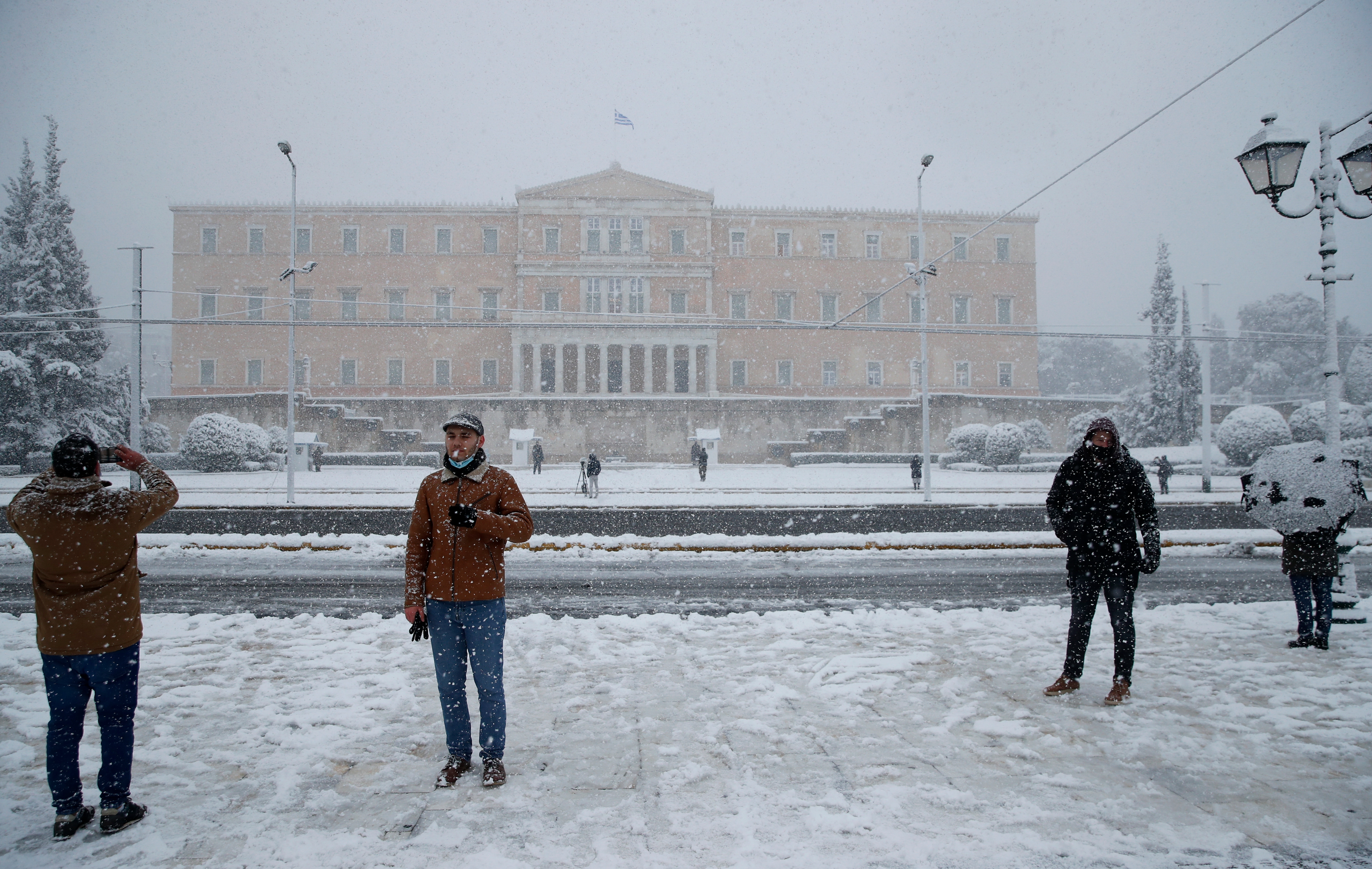 People take photographs as snow falls in front of the Greek parliament in Athens. (AP) People take photographs as snow falls in front of the Greek parliament in Athens. (AP)