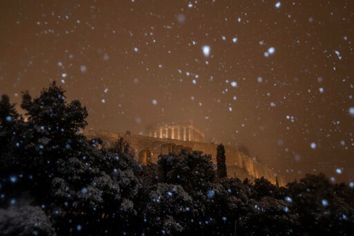 The ancient Parthenon temple on the Acropolis hill is illuminated during a snowfall in central Athens. (AP) The ancient Parthenon temple on the Acropolis hill is illuminated during a snowfall in central Athens. (AP)