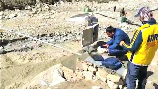 SDRF personnel setting up a siren-based early-warning water level sensor system for a sudden surge in Rishiganga waters in Chamoli district. (HT Photo)
