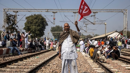 A demonstrator with a farm union's flag while blocking railway tracks in Sonipat on February 18. The farmers have asserted that the protests will go indefinitely till the three reform laws enacted by the government in September last year are completely rolled back.(Danish Siddiqui / REUTERS)