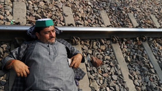 A farmer lies across a rail track while protesting at Modinagar railway station in Ghaziabad district on February 18. The farmers protests at Delhi borders continue with 11 rounds of talks between their leaders and the central government having failed to break the deadlock.(Anindito Mukherjee / Bloomberg)