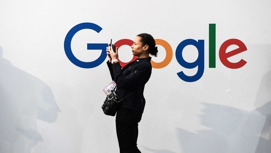 A woman takes a picture with two smartphones in front of the logo of the US multinational technology and Internet-related services company Google.(AP)