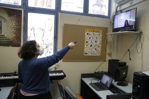 Computer teacher Evi Kontopoulou uses a remote control to find Prospathodas TV, or Trying TV, the channel of Avlonas prison school.(AP) Computer teacher Evi Kontopoulou uses a remote control to find Prospathodas TV, or Trying TV, the channel of Avlonas prison school.(AP)
