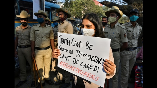 A woman holds a placard next to policemen during a protest against the arrest of climate activist Disha Ravi, Bengaluru, February 15, 2021 (REUTERS)