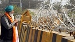 A farmer stands next to concertina wire during an ongoing protest against the new farm laws, at the Singhu Border in New Delhi. (ANI Photo) A farmer stands next to concertina wire during an ongoing protest against the new farm laws, at the Singhu Border in New Delhi. (ANI Photo)