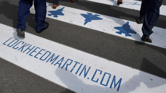 Trade visitors are seen walking over a road crossing covered with Lockheed Martin branding at Farnborough International Airshow.(File Photo / REUTERS)