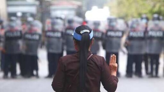 A female protester flashes the three-fingered salute in front of police in Mandalay, Myanmar,(AP) A female protester flashes the three-fingered salute in front of police in Mandalay, Myanmar,(AP)