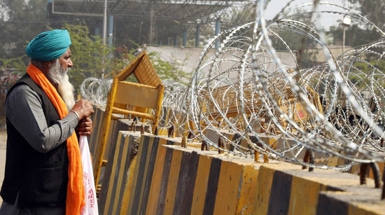 A farmer stands next to concertina wire during an ongoing protest against the new farm laws, at the Singhu Border in New Delhi. A farmer stands next to concertina wire during an ongoing protest against the new farm laws, at the Singhu Border in New Delhi.