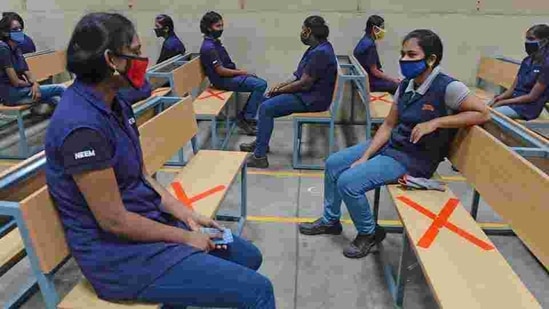 Industrial workers sit while maintaining social distancing at an assembly unit of Royal Enfield motorcycles in Oragadam on June 9.(AFP File Photo)