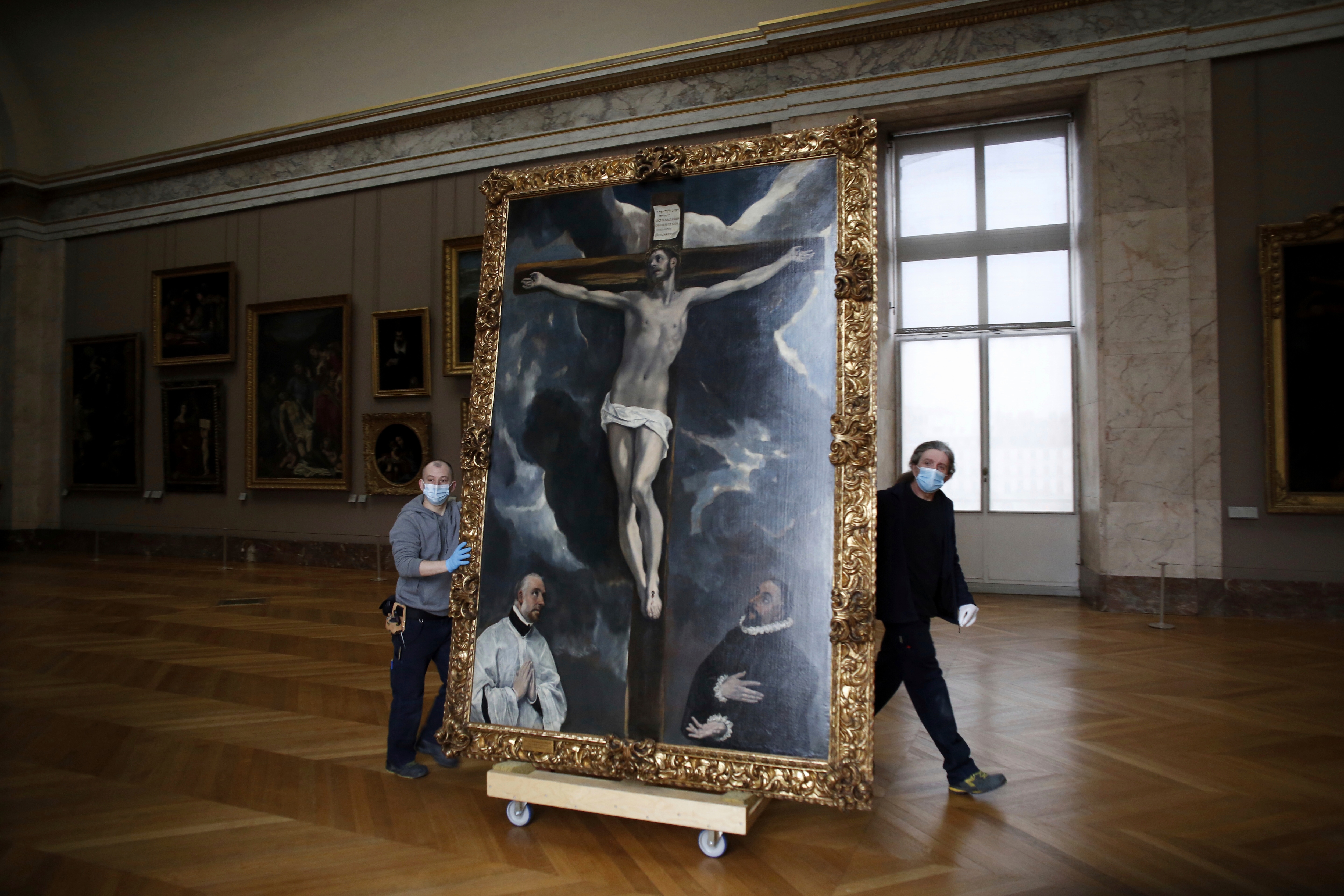 Workers at the Louvre museum transport a painting called Christ on the Cross Adored by Two Donors by Spanish painter El Greco.(AP) Workers at the Louvre museum transport a painting called Christ on the Cross Adored by Two Donors by Spanish painter El Greco.(AP)