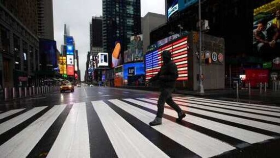 A man crosses the street in a nearly empty Times Square, which is usually very crowded on a weekday morning in New York, March 23, 2020. (AP Photo/Mark Lennihan)(AP)