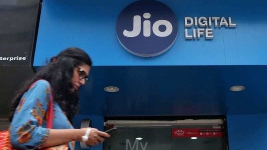 A woman checks her mobile phone as she walks past a mobile store of Reliance Industries' Jio telecoms unit, in Mumbai. (Reuters)