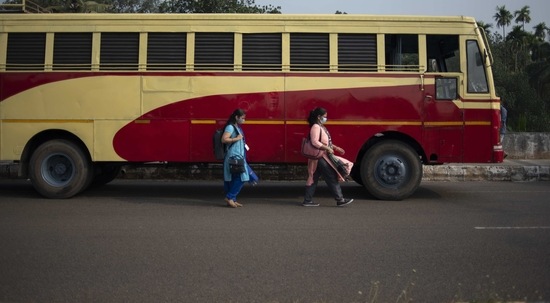 Women wearing masks as a precaution against the coronavirus walk past a public transport bus in Kochi, Kerala. (AP Photo) Women wearing masks as a precaution against the coronavirus walk past a public transport bus in Kochi, Kerala. (AP Photo)