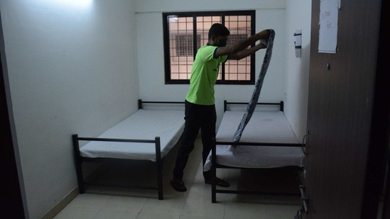 A municipal worker prepares bedding as quarantine centers were reactivated in light of rising coronavirus cases, in Thane on February 19. Maharashtra Chief minister Uddhav Thackeray on February 21 hinted at a return to lockdown after monitoring the situation for the next eight days. Last week, mayor Kishori Pednekar had also hinted at a night curfew.(Praful Gangurde / HT Photo)