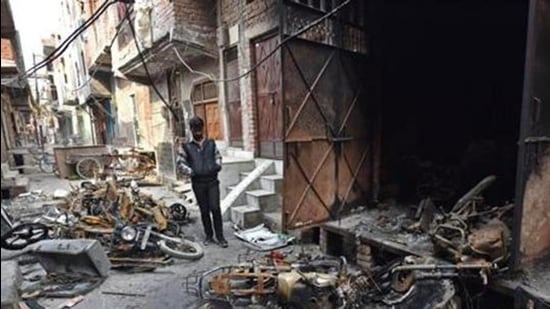 A man stands near burnt motorcycles in a riot-affected area, at Shiv Vihar, in New Delhi on March 2, 2020. (HT archive)